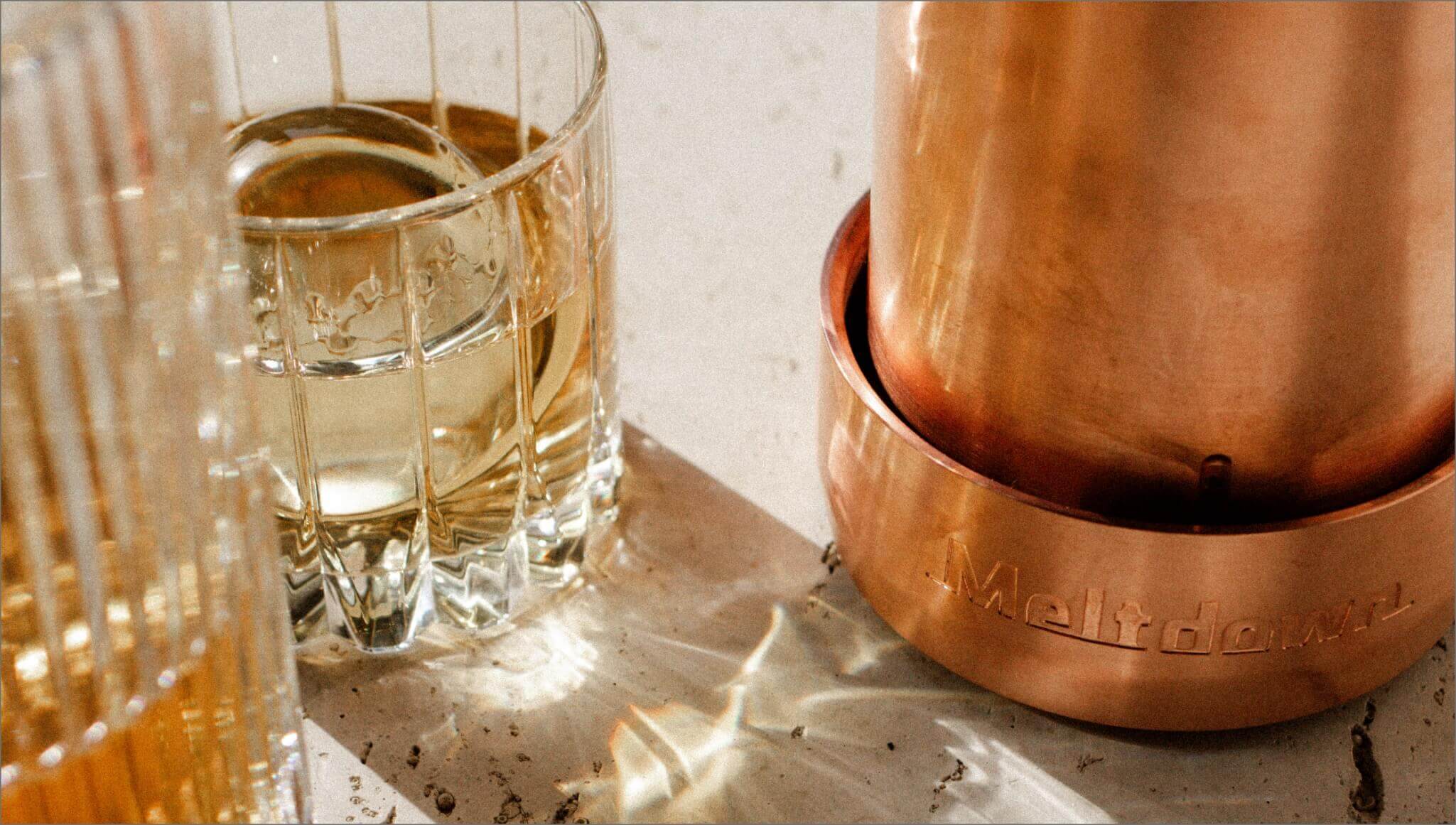 Meltdown Mogul copper ice press with Old Fashioned glass sitting on granite countertop