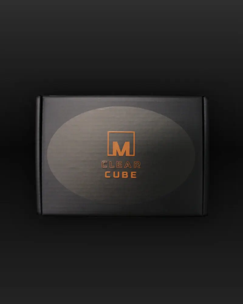 A black rectangular box, resembling a clear ice maker, displays an orange logo and Meltdown Clear Cube 2-Pack in the center, set against a dark gradient background.