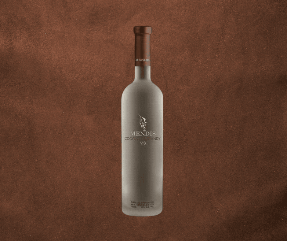 A frosted glass bottle of Mendis Coconut Brandy V.S. with a brown cap, displayed against a textured brown background. The bottle features silver text and a logo on the front.